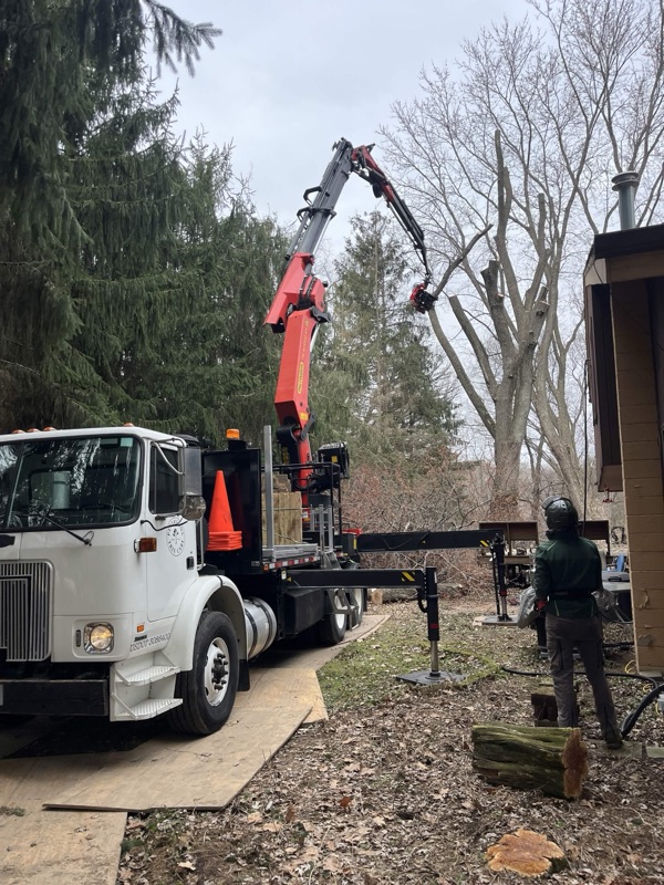A red crane truck setting up behind a Wisconsin home for a tree removal job